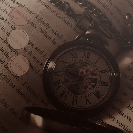 an old pocket watch sitting on top of a book with chain around it's neck