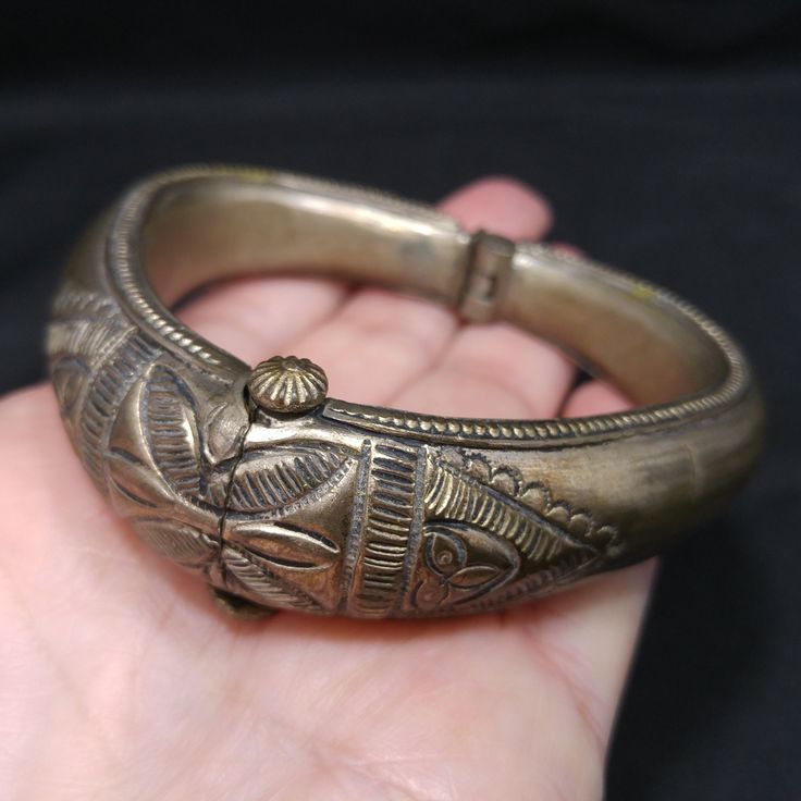 *Description: This is a great embossed design tribal bracelet with a hinge and plunger clasp which makes it very easy to take on and off from the 1940s. The plunger stays attached so you don't have to worry about loosing it. The bracelet has a gold wash, which I tested at 10K gold surface metal. The bracelet under the gold wash is a non-magnetic brass metal; probably mostly hollow. The shape of the bracelet is very unique and is more of a triangular shape with the flat portion on the bottom behi Antique Bronze Bracelets With Intricate Design, Vintage Brass Bracelet With Intricate Design, Vintage Hinged Bangle Bracelet, Vintage Ceremonial Metal Jewelry, Vintage Bronze Cuff Bracelet With Intricate Design, Vintage Ceremonial Cuff Bracelet With Intricate Design, Antique Jewelry Bangle With Antique Finish, Antique Finish Bangle Jewelry, Ornate Bangle Bracelet With Antique Finish