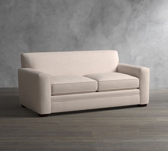 a white couch sitting on top of a hard wood floor next to a gray wall