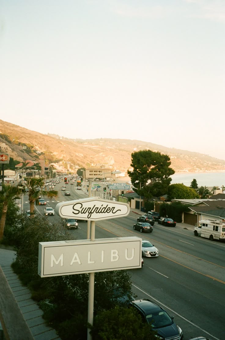 a street sign on the side of a road with cars parked in front of it