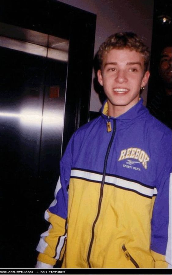 a young man in a yellow and blue jacket standing next to an open elevator door