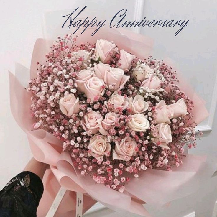 a person holding a bouquet of pink roses in front of a white wall and door