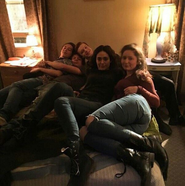 four people are laying on a bed with their arms around each other