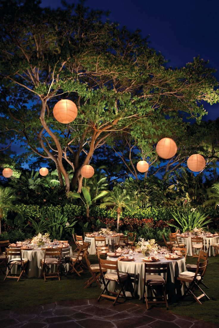 an outdoor dinner with paper lanterns hanging from the trees