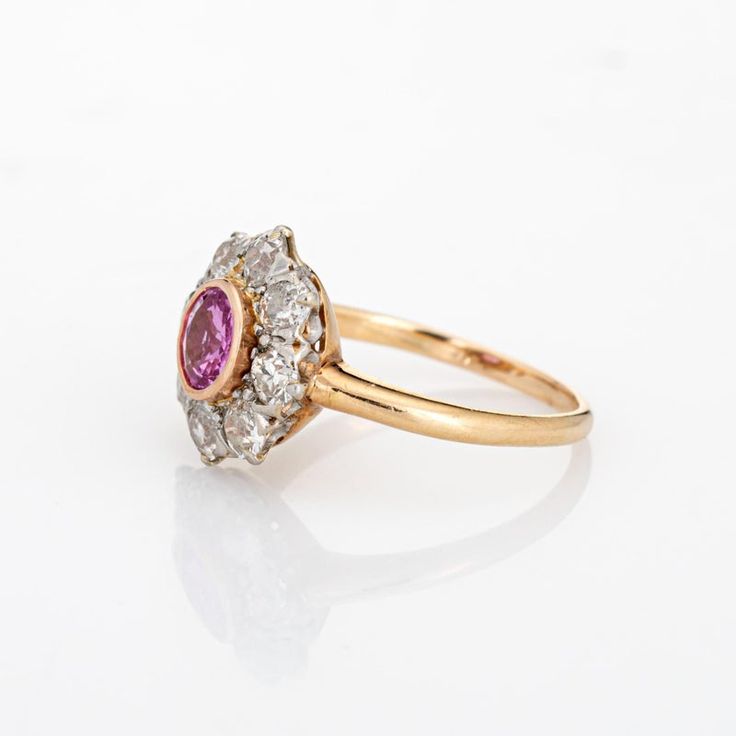 Stylish antique Edwardian pink sapphire & diamond cluster ring crafted in 14k yellow gold (circa 1900s to 1910s). One centre set pink sapphire is estimated at 0.50 carats, accented with eight estimated 0.15 carat old mine cut diamonds. The total diamond weight is estimated at 1.20 carats (estimated at I-J and SI1-I1 clarity). The sapphire is in very good condition and free of cracks or crisps.   The classic cluster design highlights a halo of diamonds surrounding the vibrant and lively pink sapp Old Cut Diamond Ring, Classic Pink Cluster Ring For Formal Occasions, Classic Pink Ruby Ring With Halo Setting, Classic Ruby Ring With Rose Cut Diamond Cluster, Classic Pink Cluster Ring With Prong Setting, Classic Pink Cluster Ring With Center Stone, Classic Pink Diamond Cluster Ring, Classic Pink Cluster Ring With Halo Setting, Classic Pink Cluster Ring For Anniversary