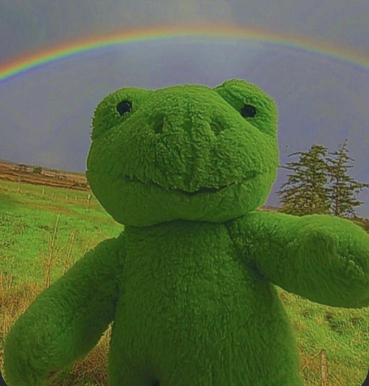 a large green teddy bear with a rainbow in the background