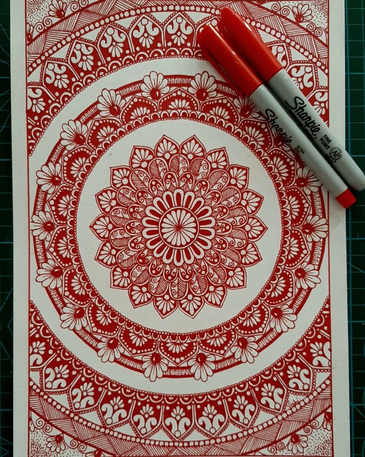 a red and white drawing on paper next to a marker