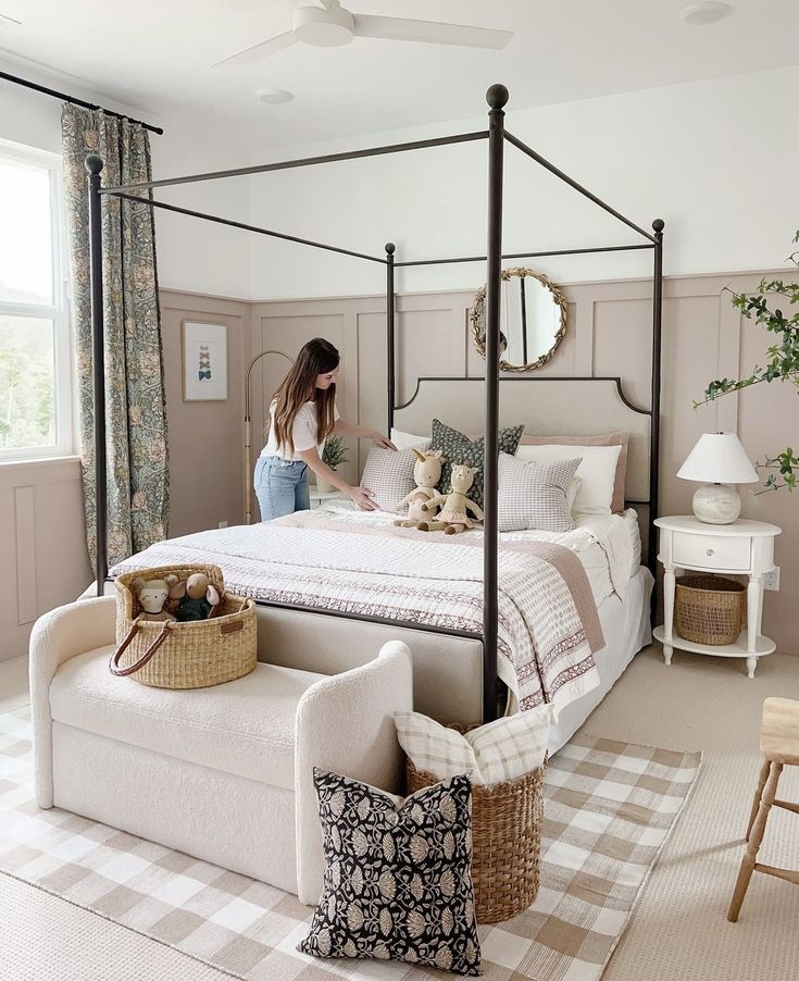 a woman sitting on top of a bed in a bedroom next to a table and chairs