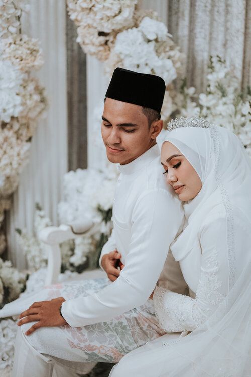 a man and woman sitting next to each other in front of a flower covered wall