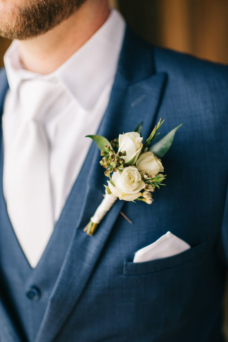 a man wearing a blue suit and white boutonniere with flowers on the lapel