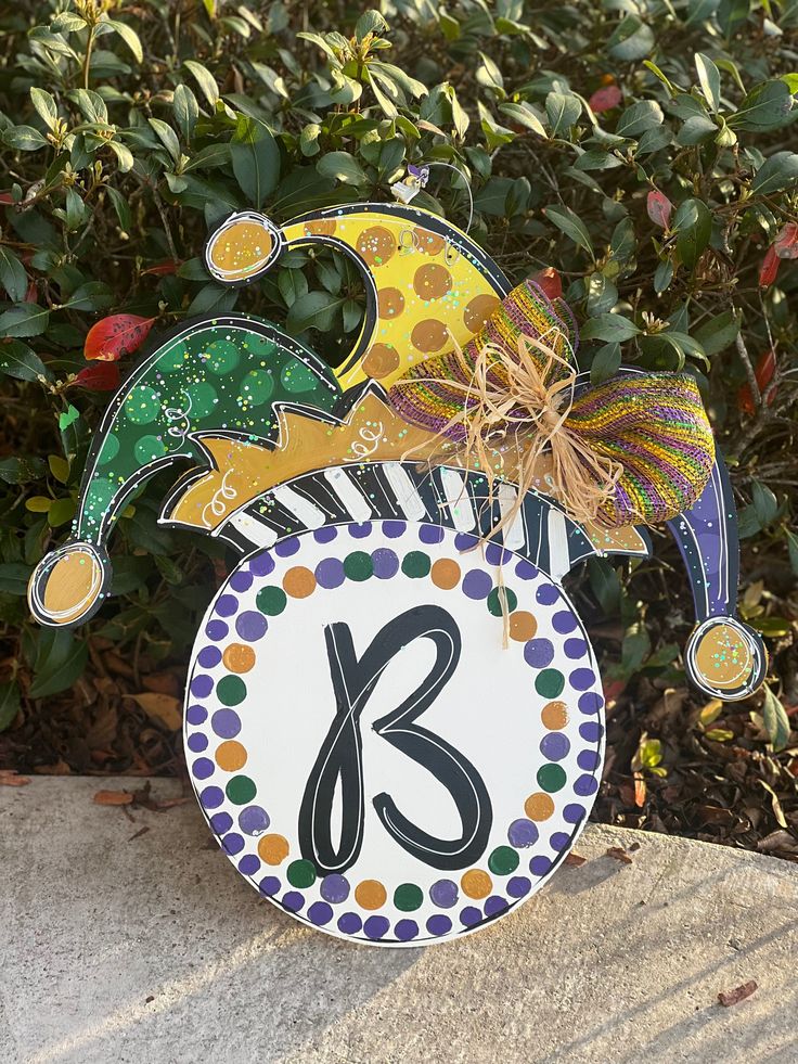 a colorful clock sitting on top of a cement block next to bushes and trees with decorations