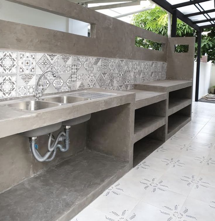 a bathroom with concrete sinks and tiled walls