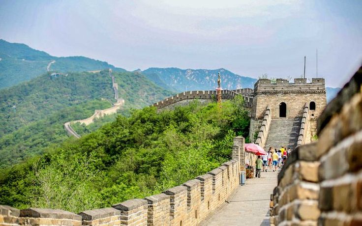 the great wall of china with people walking on it and mountains in the background,