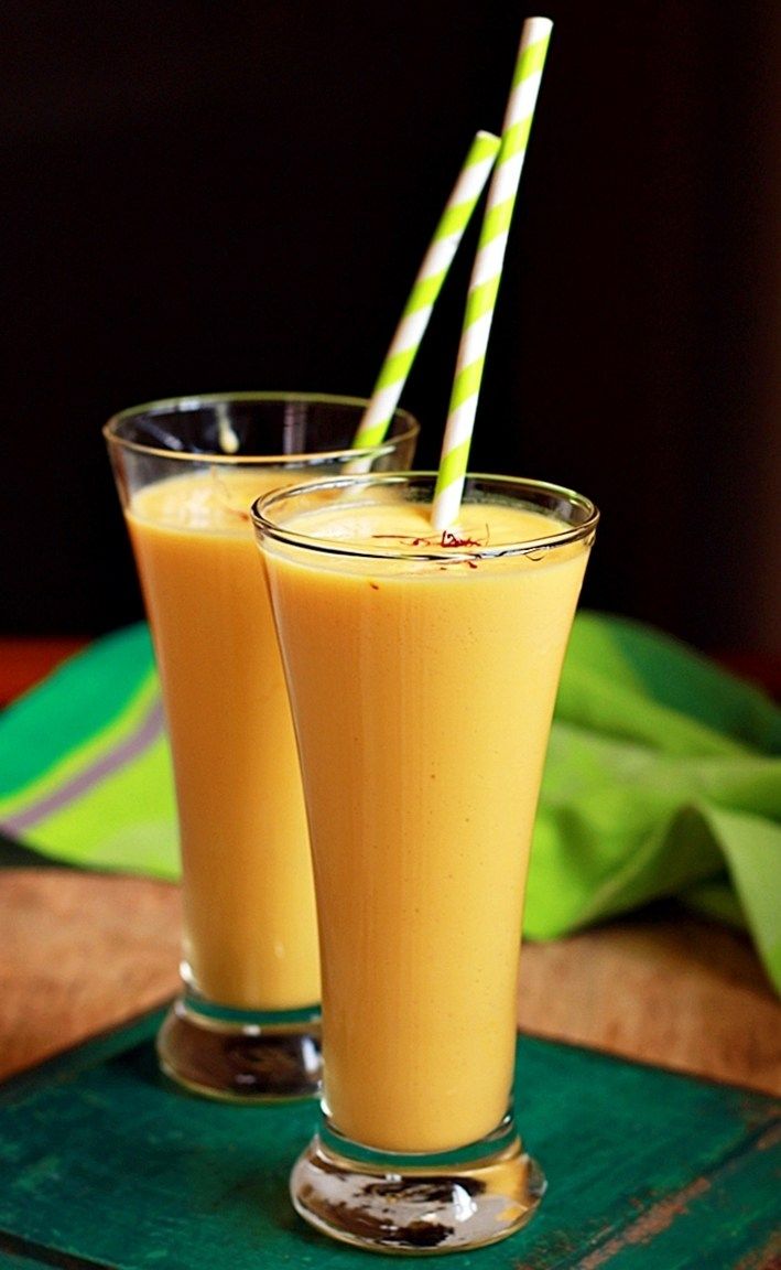 two glasses filled with orange juice on top of a wooden table