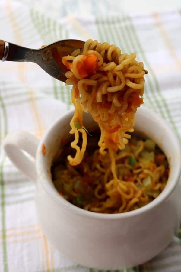 a spoon full of noodles being lifted from a cup