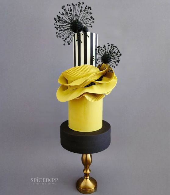 a yellow hat with black and white decorations on top is sitting on a gold stand