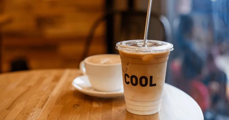 a cup of coffee sitting on top of a wooden table