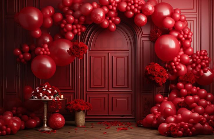 a bunch of balloons that are in front of a red wall with flowers and a cake