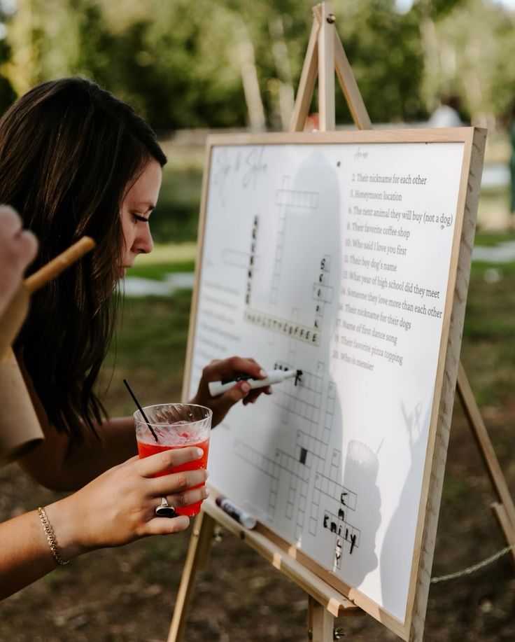 a woman holding a drink in front of a sign that has writing on it and pointing to the side