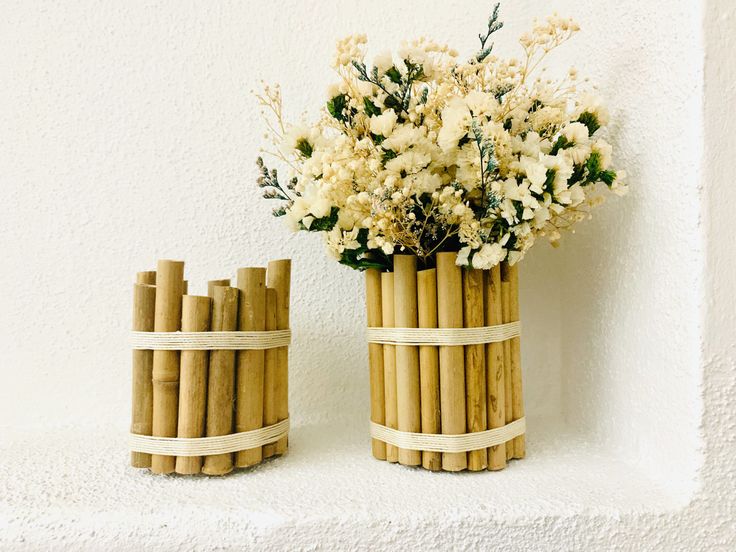 two vases made out of bamboo sticks with flowers in them