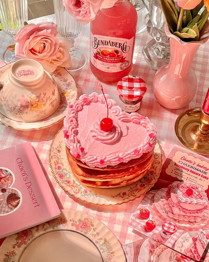 a table topped with lots of pink flowers and cake covered in frosting on top of plates