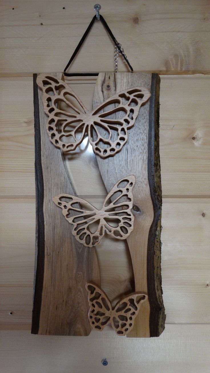 a wooden wall hanging with two butterflies on it's side and one is cut out from wood