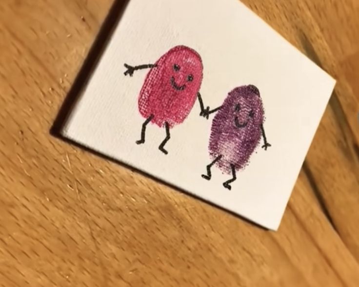 two little cartoon characters are holding hands on a piece of white paper with colored crayons in the background