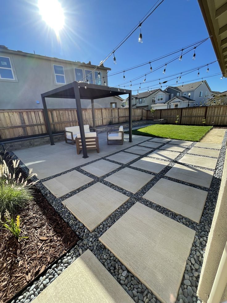 an outdoor patio with stone pavers and string lights in the back yard, surrounded by grass