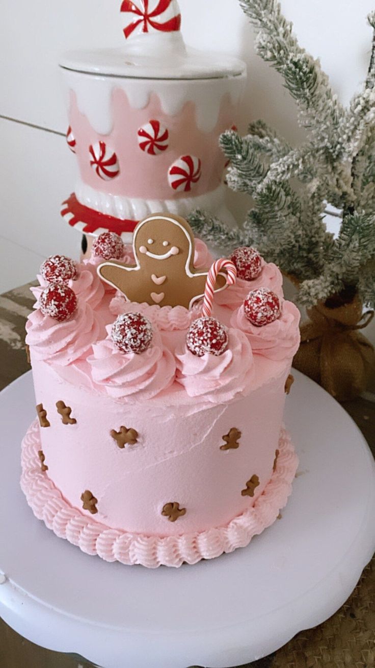 a pink frosted cake sitting on top of a white plate next to a christmas tree