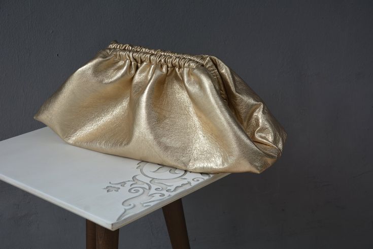 Introducing our luxurious Gold genuine Metallic leather dumpling cloud clutch, a statement accessory that exudes elegance and sophistication. This Large metallized lambskin cloud bag is perfect for those who love to make a bold fashion statement. With its oversized puffball design, this handbag purse is sure to turn heads wherever you go. Crafted with high-quality materials and intricate detailing, this clutch is a must-have for any fashion-forward individual looking to elevate their style game. Metallic Clutch Bag, Bags 2024, Metallic Clutch, Cloud Bag, Folding Bag, Evening Outfits, Leather Clutch Bags, Manado, Soft Tops