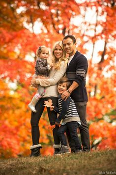 a family posing for a photo in front of colorful trees