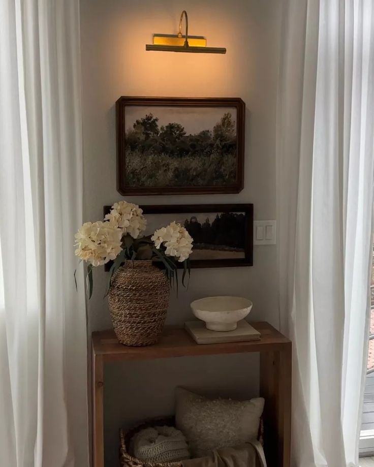 a vase with white flowers sitting on top of a wooden shelf next to a window