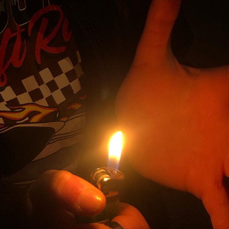 a person holding a lit candle in their left hand and pointing at it with both hands