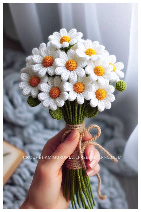 a hand holding a bouquet of white and yellow flowers with twine wrapped around it