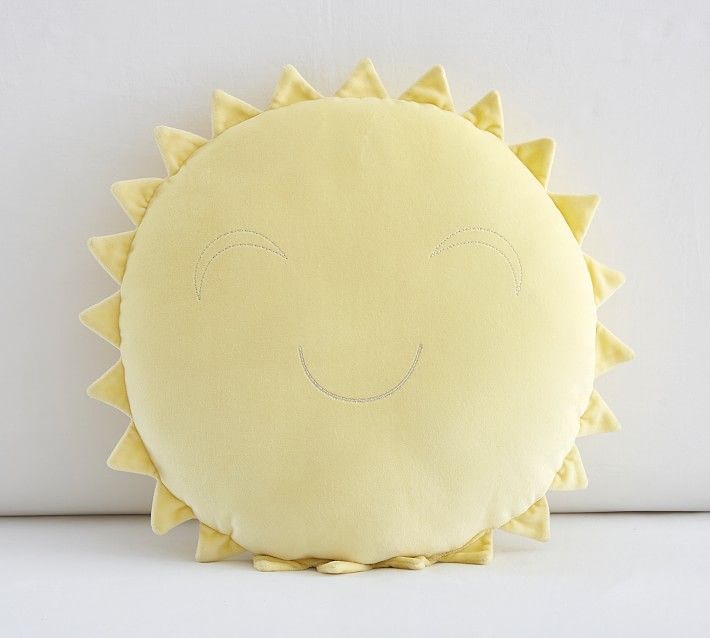 a yellow sun pillow sitting on top of a white table