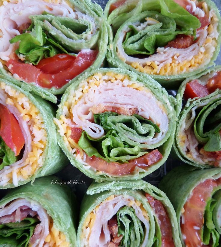 many different types of food are arranged in the shape of rolls with meat, lettuce and tomatoes