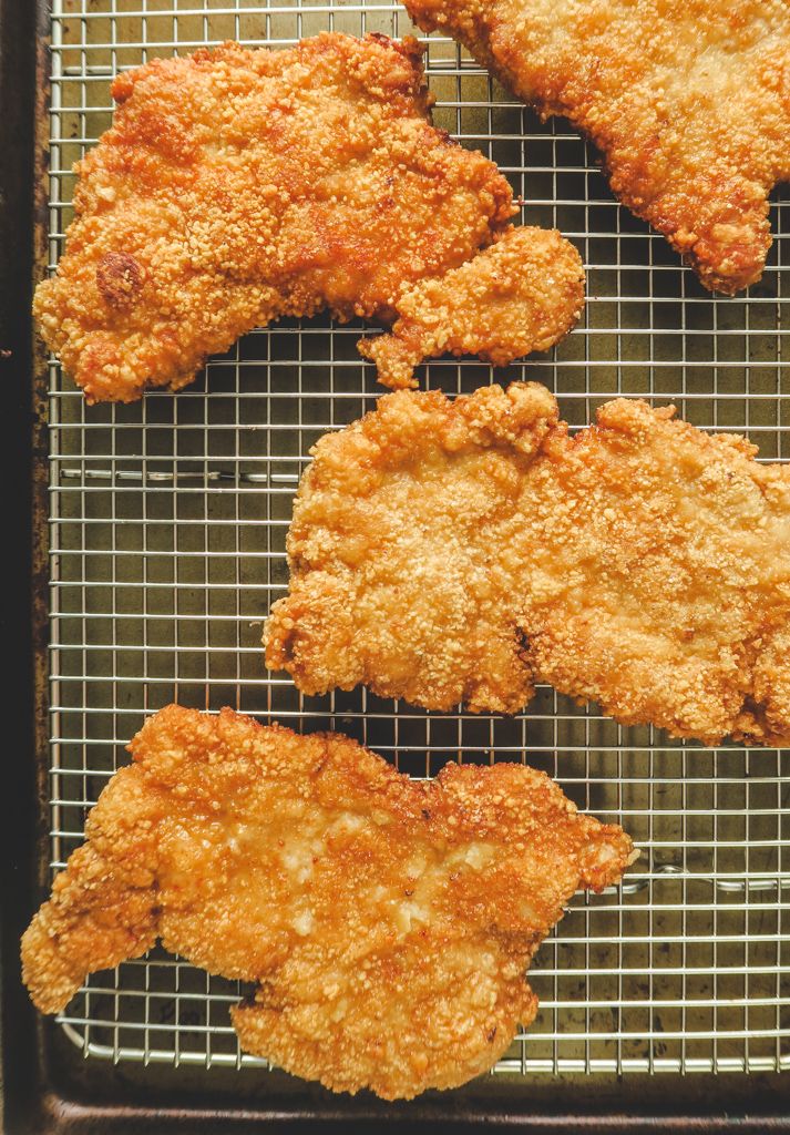 four fried chicken pieces on a cooling rack