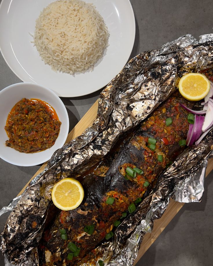 an image of fish in foil with rice and lemons