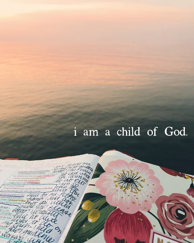 an open book with the words i am a child of god written on it next to water