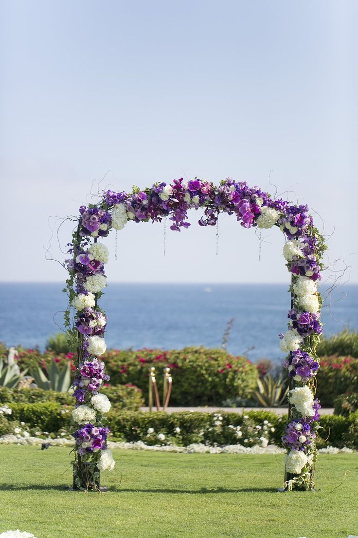 an outdoor wedding setup with flowers and greenery on the lawn by the ocean in front of blue sky