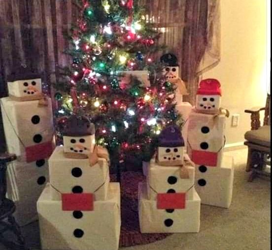 a christmas tree decorated with snowmen and presents in front of a small lite - up christmas tree