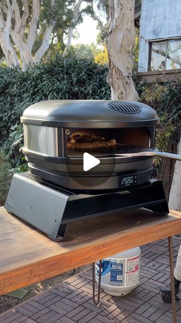 a man standing next to a table with an open oven on it's side