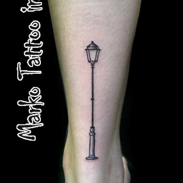 a foot with a lamp post tattoo on it