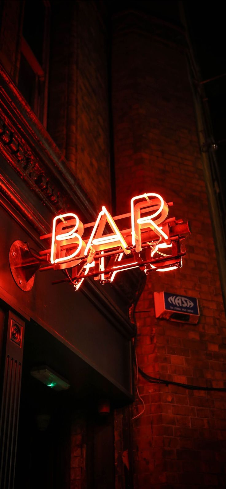 a neon sign that reads bar life on the side of a brick building at night