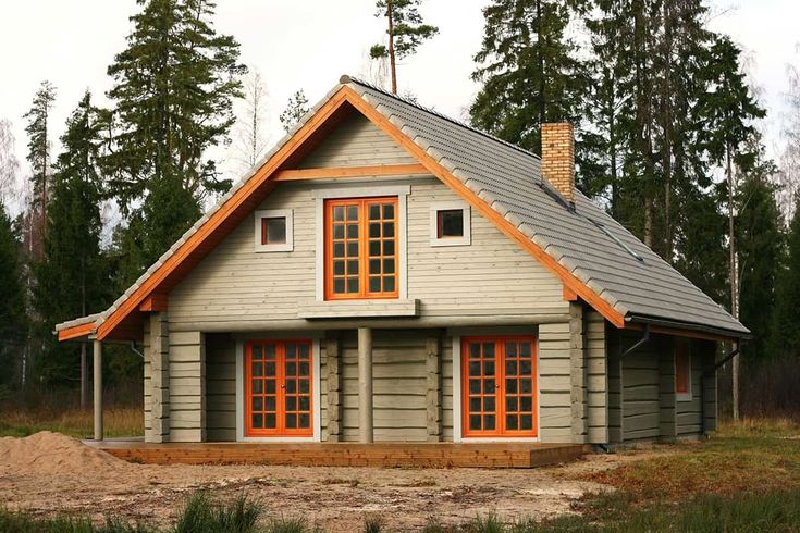 a small wooden house with orange windows in the woods