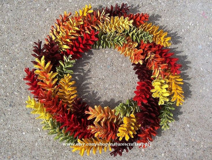 a colorful wreath made out of leaves on the ground in front of a sidewalk with no one around it