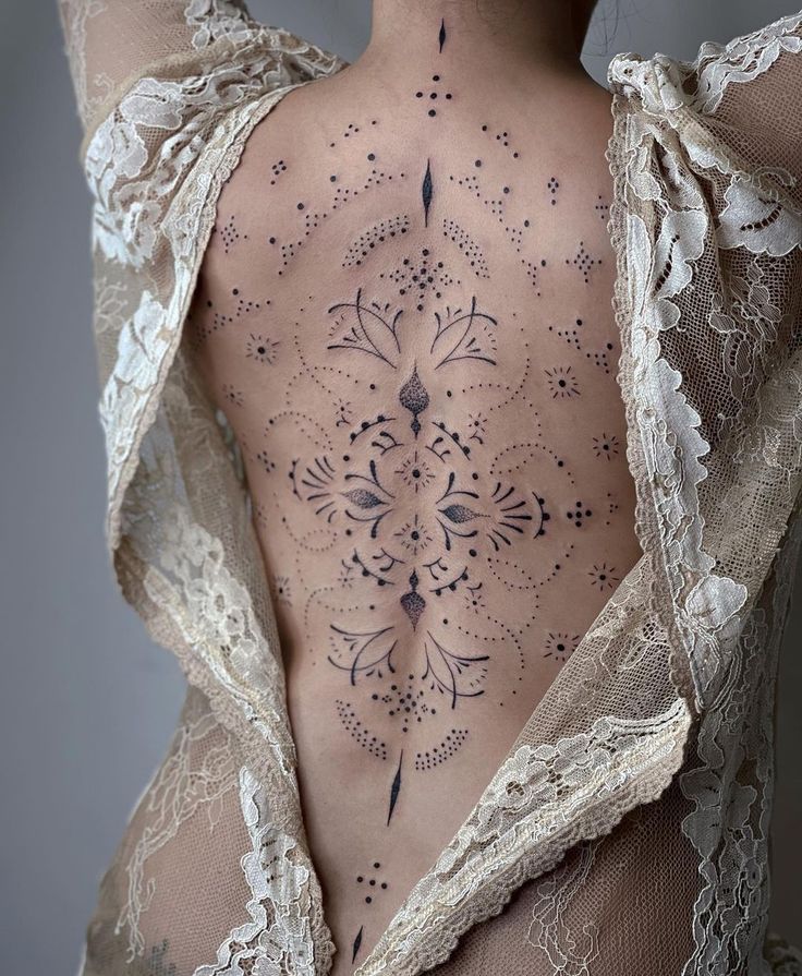 the back of a woman's body is covered with intricate tattoos and laces