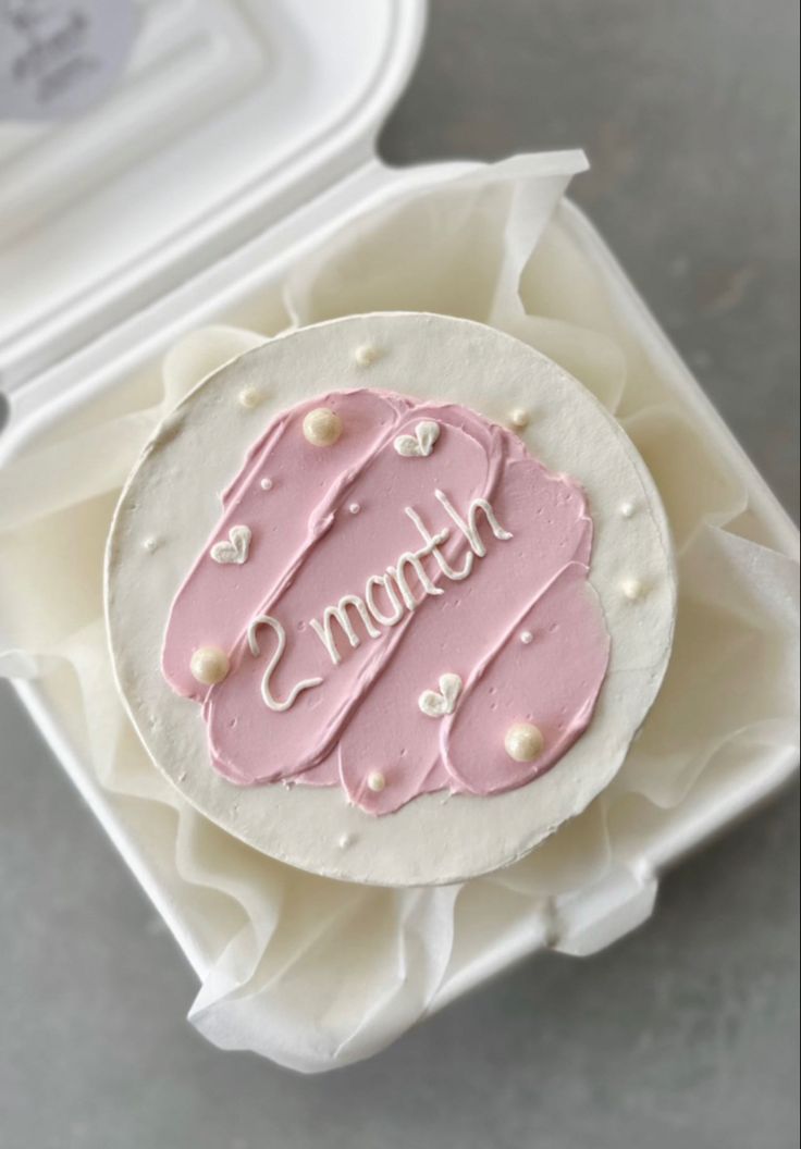 a pink frosted cake in a white box with the word monogram on it