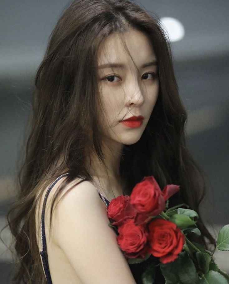 a woman with long dark hair holding red roses