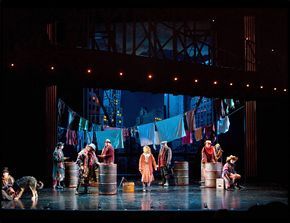 a group of people standing on top of a stage next to barrels with clothes hanging from them